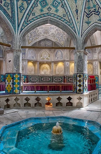 Baño tradicional con cúpula de azulejos y una fuente en una pileta turquesa