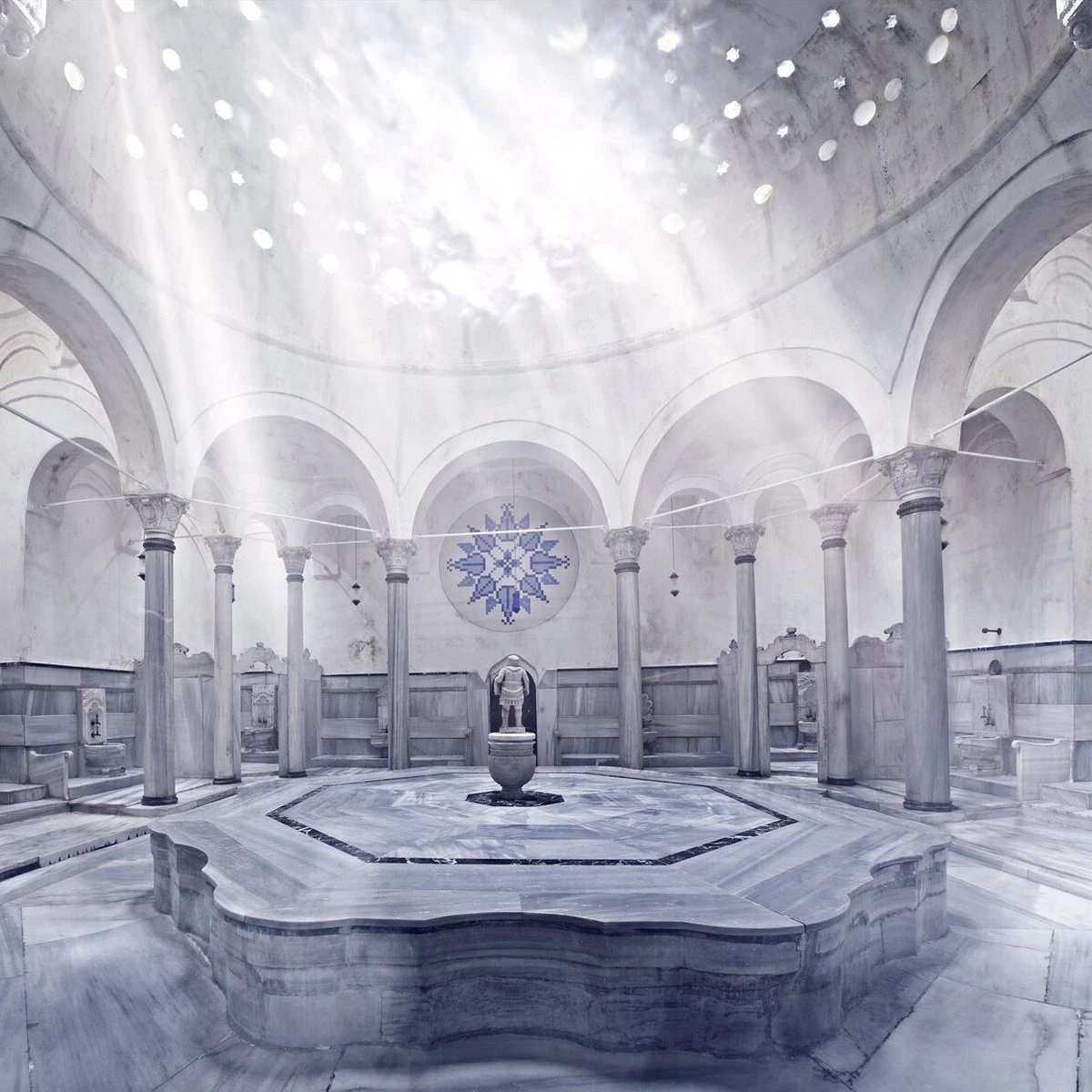 Interior de un hamam con cúpula y rayos de luz sobre el mármol