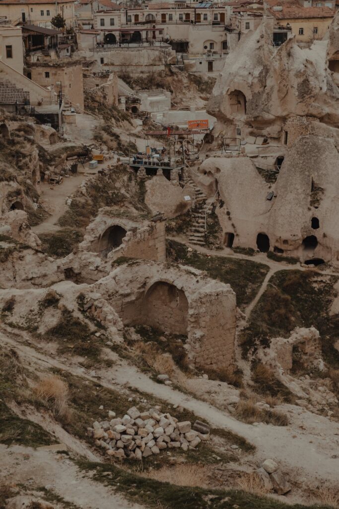 Old residential houses located on grassy ground in rocky area with shabby stony formations of national park in Cappadocia in Turkey