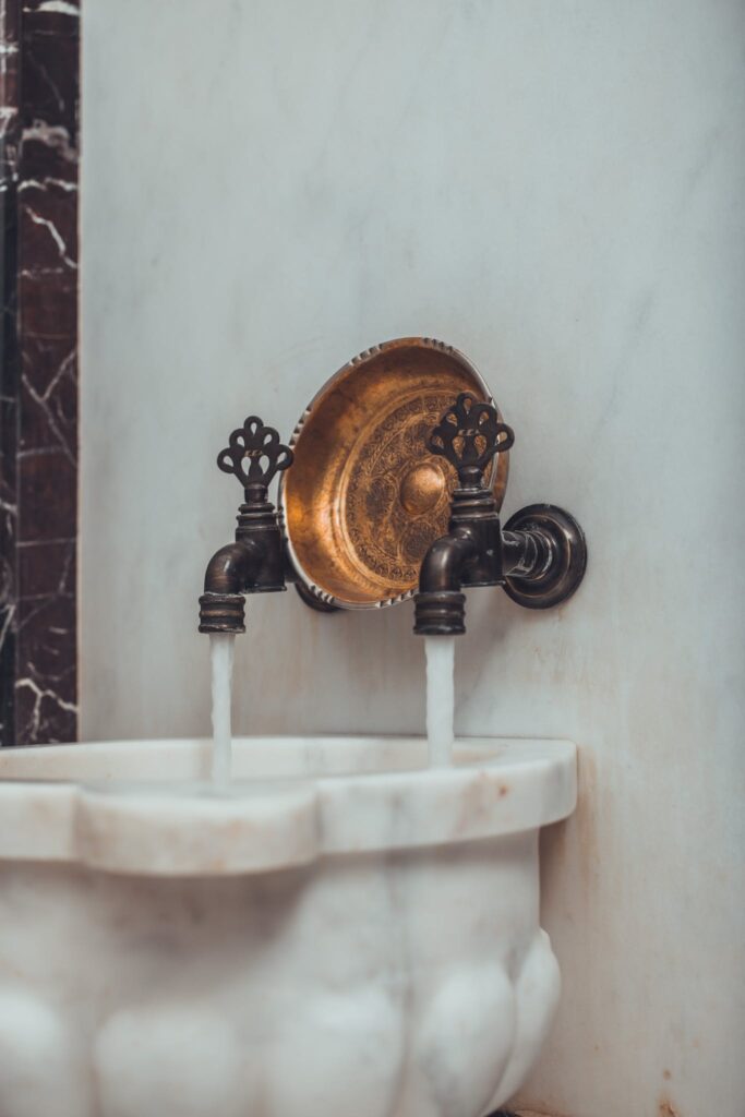 A brass faucet with a marble sink in front of it